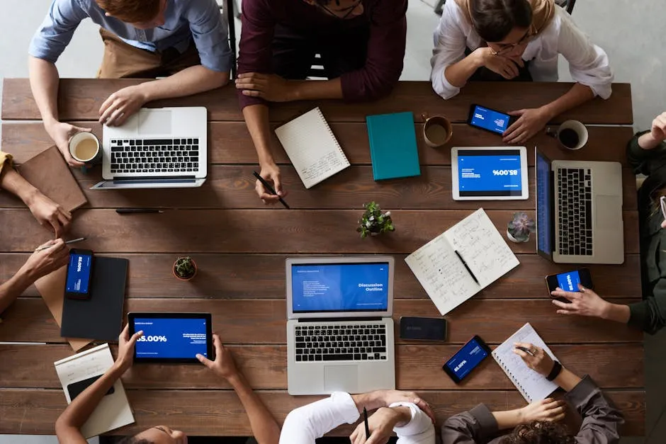 Team collaborating at a tech startup office with laptops and whiteboards